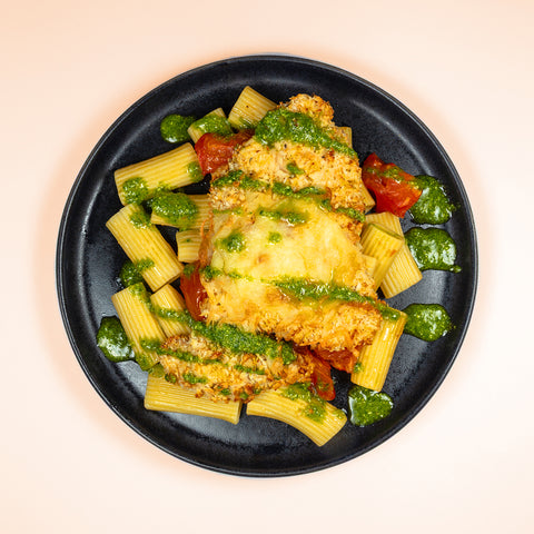 Frango à parmegiana com pesto, rigatoni e tomate assado