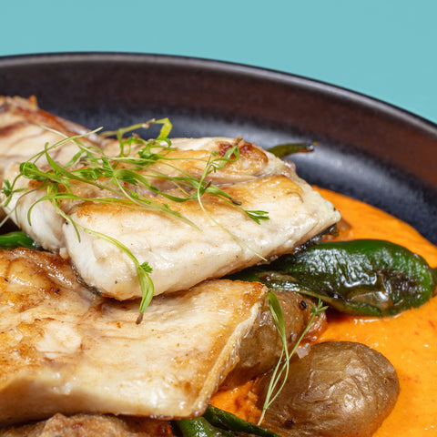 Robalo grelhado, batata a murro, pimentos padrón e romesco